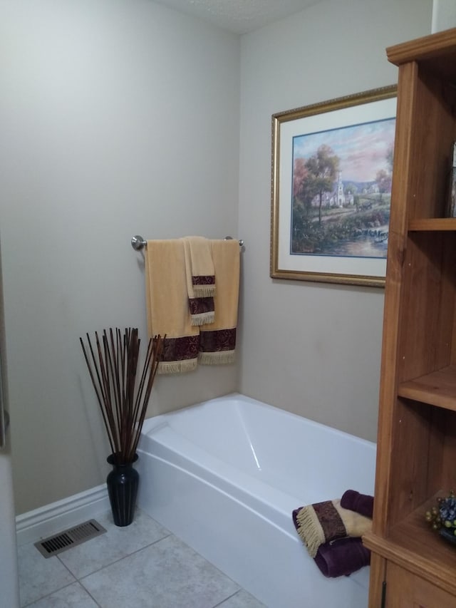 bathroom featuring a bath, baseboards, visible vents, and tile patterned floors