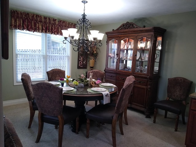 dining space featuring light carpet, baseboards, and a chandelier