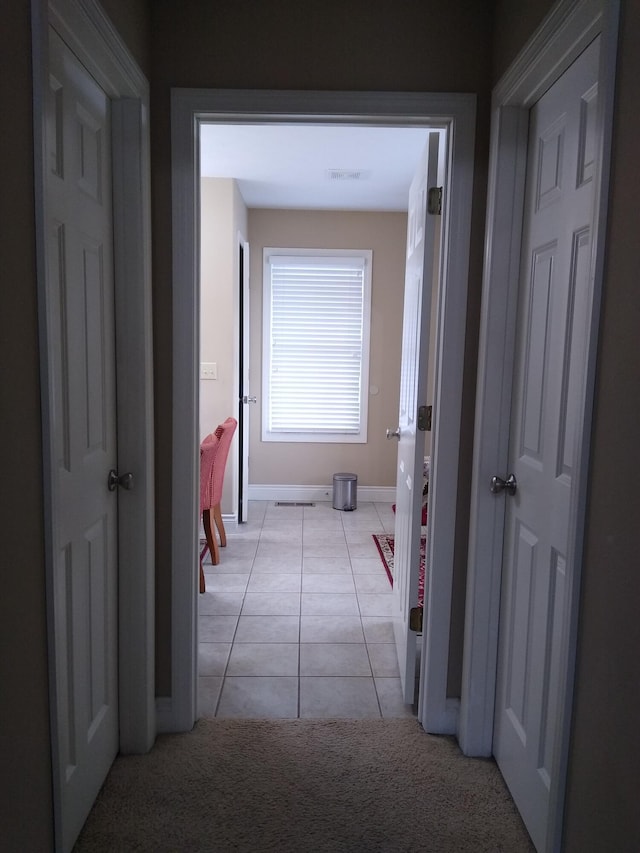 hallway featuring baseboards, visible vents, and light tile patterned flooring
