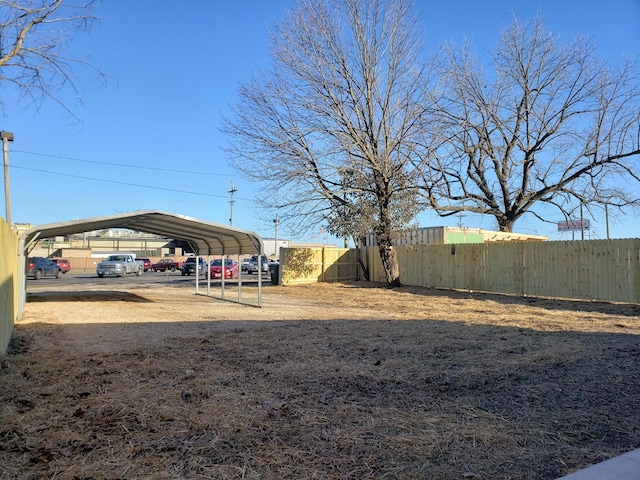 view of yard with driveway, fence, and a detached carport