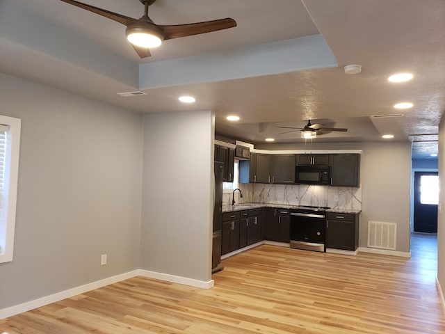 kitchen with visible vents, stove, freestanding refrigerator, a sink, and black microwave