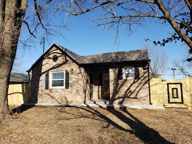 view of front of property featuring a shingled roof and brick siding