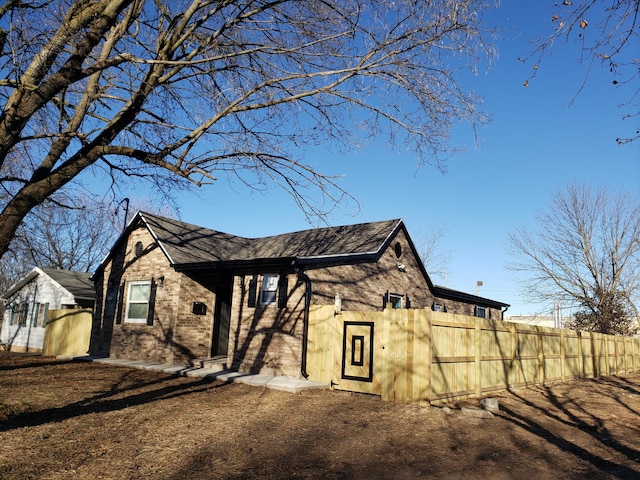 view of side of property featuring brick siding and fence