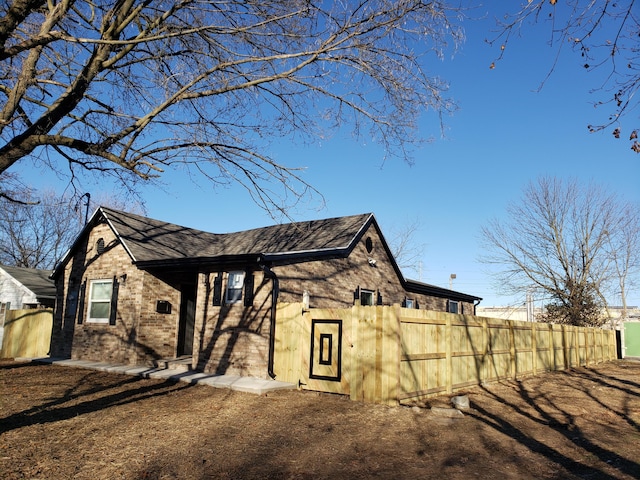 view of side of property featuring brick siding and fence