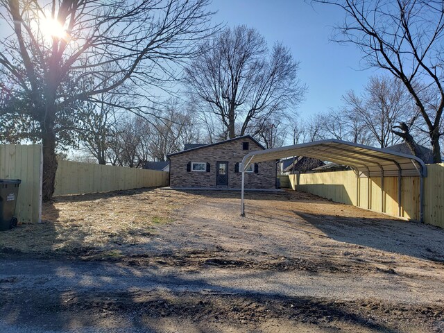 exterior space with a detached carport, fence, and dirt driveway