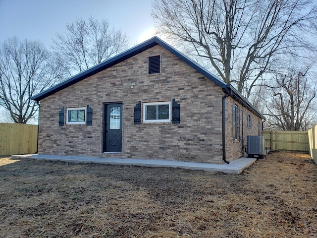 view of front of home featuring cooling unit, brick siding, and fence