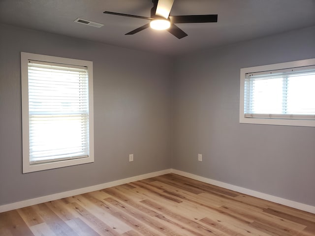 empty room with baseboards, light wood finished floors, visible vents, and a ceiling fan