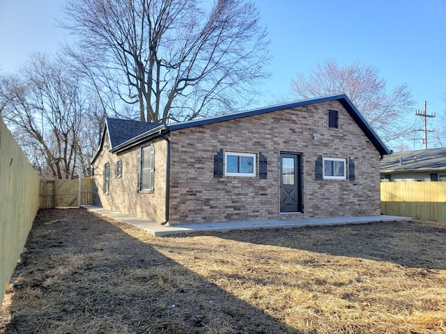 back of house featuring brick siding, a shingled roof, and a fenced backyard