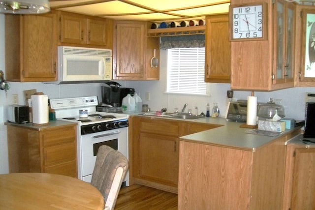 kitchen featuring light countertops, white appliances, a peninsula, and a sink