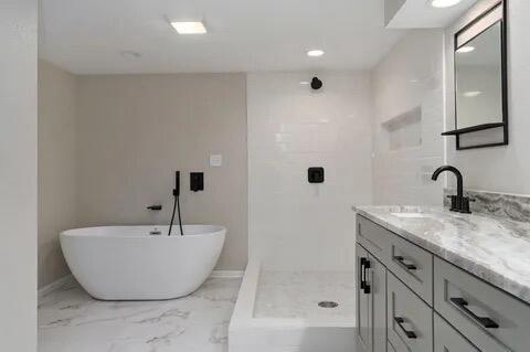 bathroom featuring baseboards, marble finish floor, walk in shower, vanity, and a freestanding tub