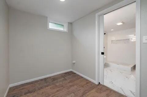 clothes washing area featuring wood finished floors and baseboards