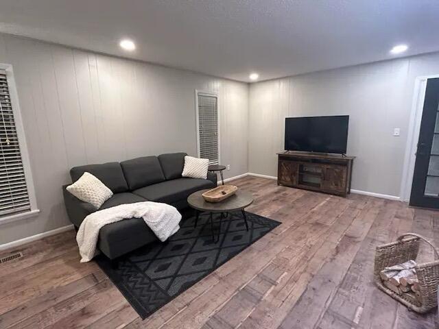 living area featuring recessed lighting, visible vents, and wood finished floors