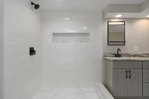 bathroom with tiled shower and vanity