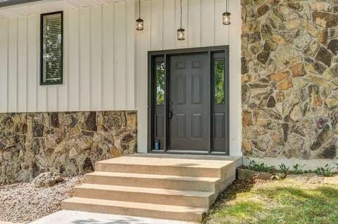 property entrance with stone siding and board and batten siding