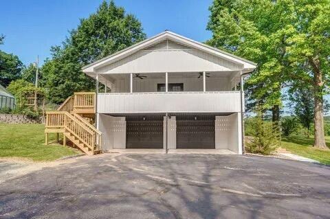 view of front of home with driveway, a garage, ceiling fan, stairway, and a front yard