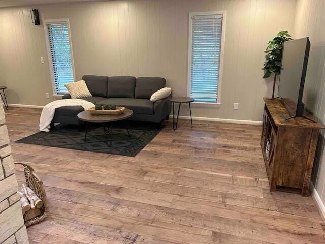 living area with a wealth of natural light, light wood-type flooring, and baseboards