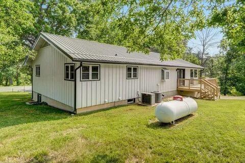 back of property featuring metal roof, a lawn, a deck, and central AC unit