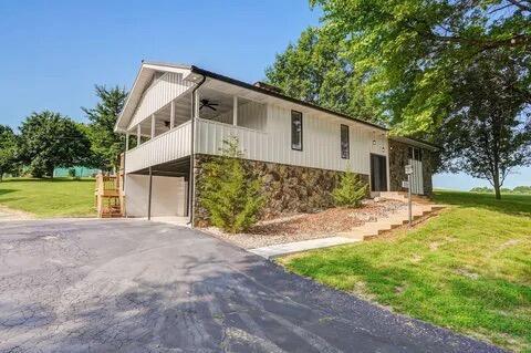 view of home's exterior featuring a ceiling fan, a yard, driveway, stone siding, and a carport