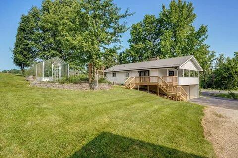 back of house featuring driveway, stairs, a lawn, and an outbuilding