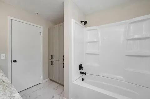 bathroom featuring marble finish floor and shower / bath combination