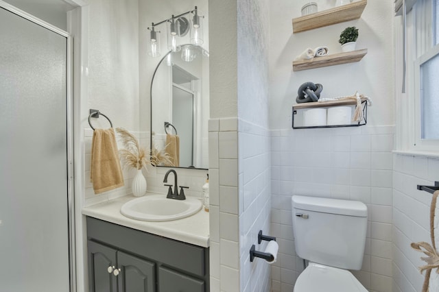 bathroom with a stall shower, tile walls, vanity, and toilet