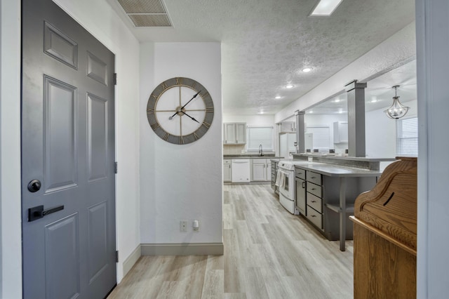 kitchen featuring a textured ceiling, white appliances, visible vents, white cabinetry, and light wood finished floors