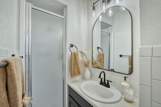 full bath with a textured wall, a shower stall, and vanity