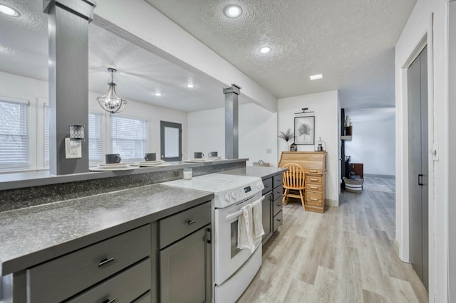 kitchen featuring electric stove, light wood-style flooring, a textured ceiling, gray cabinetry, and ornate columns