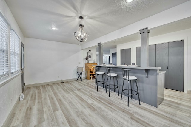 kitchen with a kitchen breakfast bar, light countertops, light wood-style flooring, and ornate columns