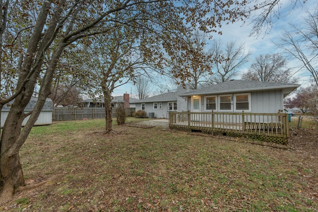 back of property with an outbuilding, a yard, fence, a shed, and a wooden deck