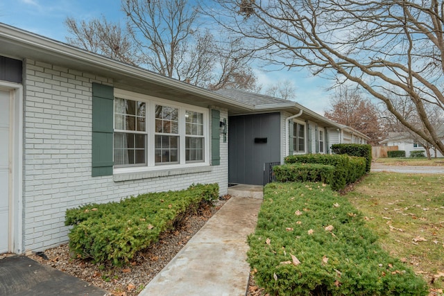 doorway to property with brick siding and a yard