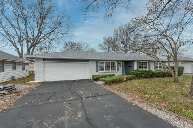 ranch-style home with a garage, aphalt driveway, roof with shingles, a front lawn, and brick siding