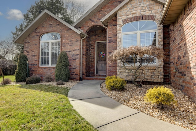 view of exterior entry featuring a yard, brick siding, and stone siding