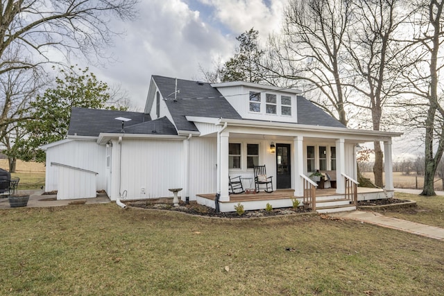 rear view of property with a porch, a lawn, a shingled roof, and a garage