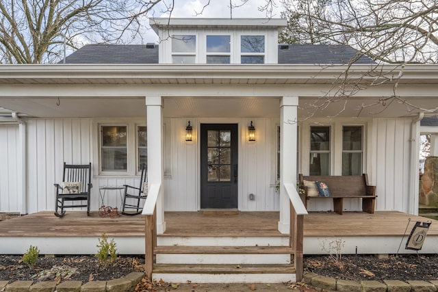 property entrance featuring covered porch, board and batten siding, and roof with shingles