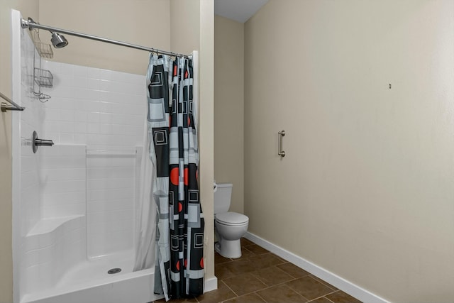 bathroom with toilet, a stall shower, tile patterned flooring, and baseboards