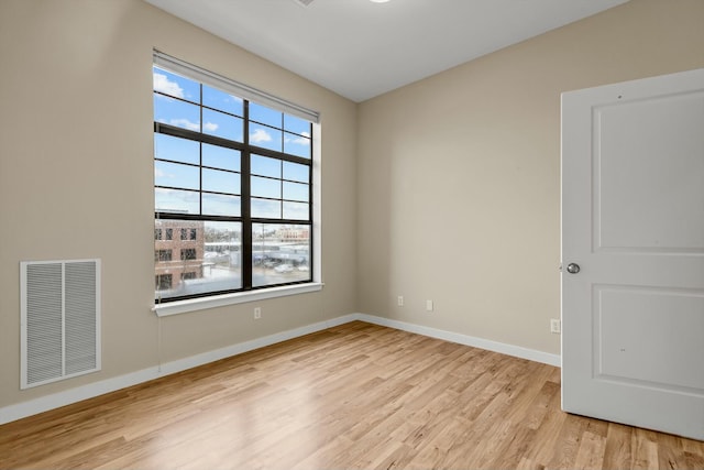 unfurnished room with light wood-type flooring, visible vents, and baseboards