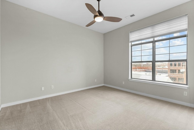 carpeted empty room featuring a ceiling fan, visible vents, and baseboards