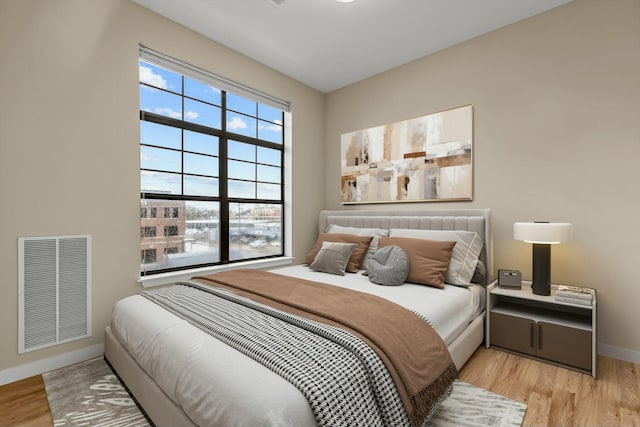 bedroom with light wood finished floors, baseboards, and visible vents