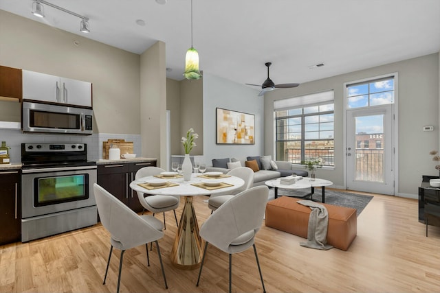 dining space with ceiling fan, light wood-style flooring, visible vents, baseboards, and track lighting