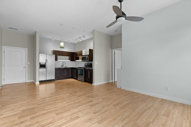 unfurnished living room with light wood-type flooring, visible vents, a sink, and baseboards