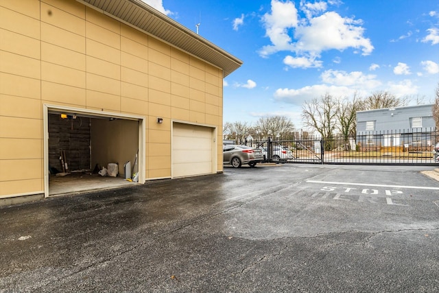 view of car parking with a garage, a gate, and fence