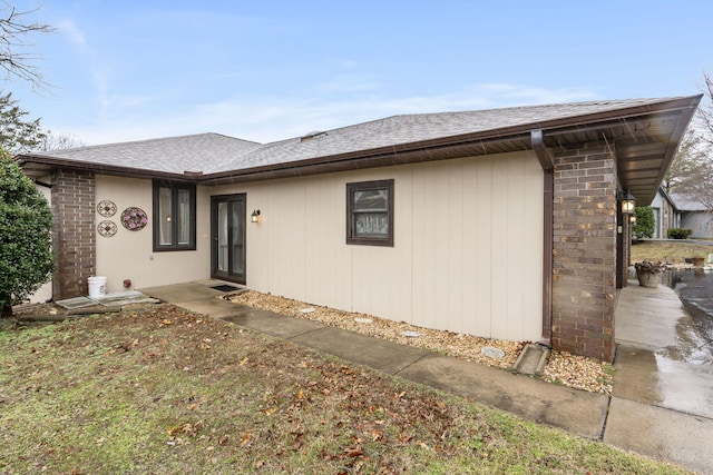 view of front of house with a shingled roof and brick siding