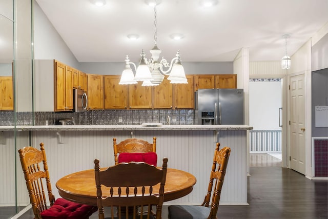 kitchen with a notable chandelier, vaulted ceiling, appliances with stainless steel finishes, dark wood-style floors, and tasteful backsplash