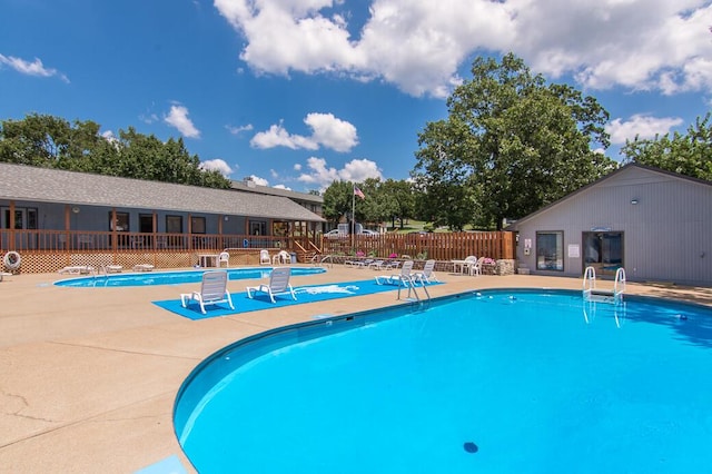 community pool with a patio area and fence