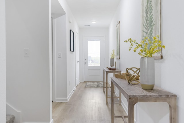 doorway with light wood-type flooring and baseboards