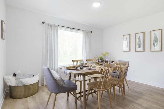 dining area with light wood-type flooring and baseboards