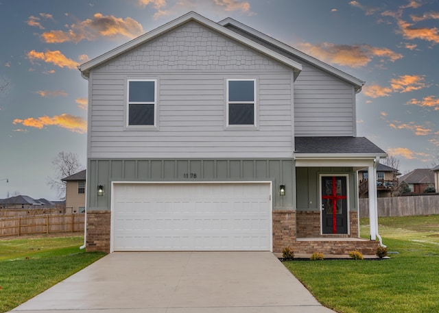 view of front of house with a yard, board and batten siding, an attached garage, and fence