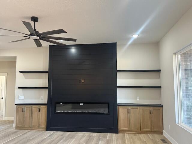 unfurnished living room with light wood-style floors, ceiling fan, visible vents, and baseboards