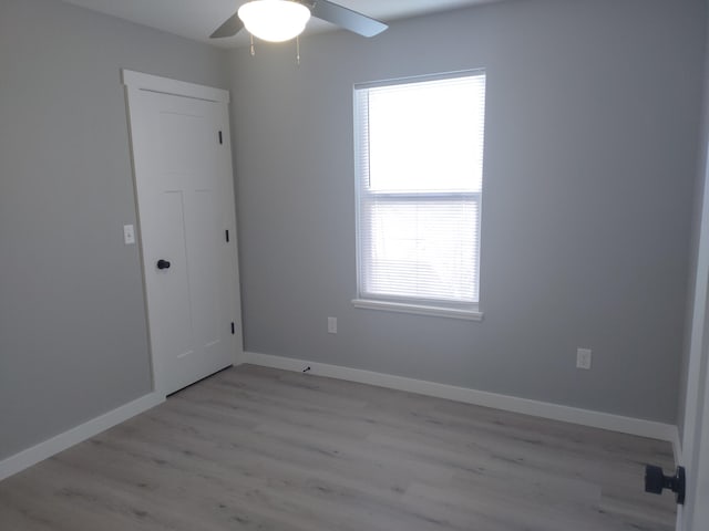 spare room with light wood-type flooring, plenty of natural light, baseboards, and ceiling fan